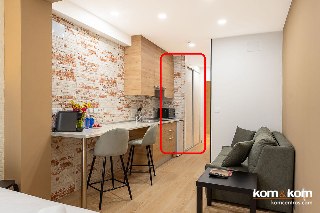 Armario empotrado a medida con puertas correderas en acabado blanco liso, dise&ntilde;ado por Kom&amp;Kom para maximizar el aprovechamiento de espacio en la entrada de apartamentos tur&iacute;sticos Emily Suits.